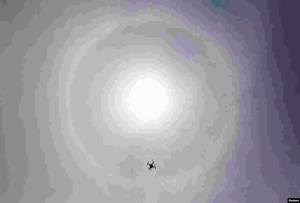 A drone flies in the sky as a solar halo is observed in Lima, March 5, 2014. The optical phenomenon is caused by refraction of sunlight through ice crystals in high clouds. 