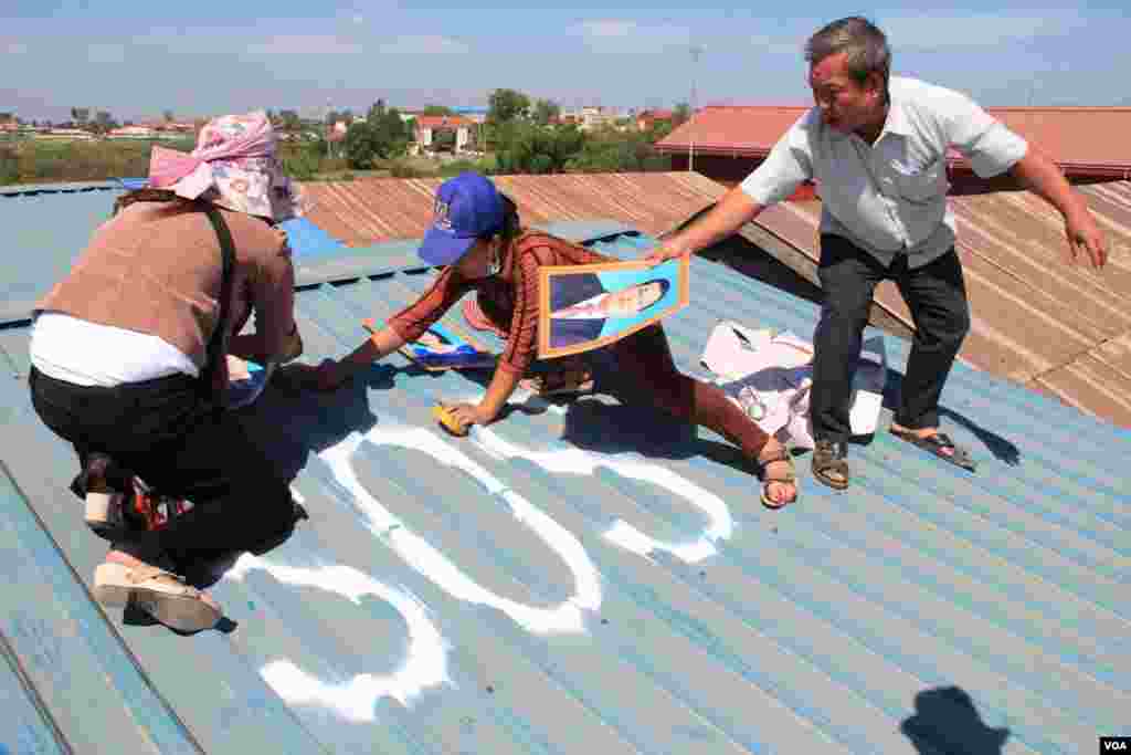 People in Tropeang Lavear display SOS messages on their roofs, which lies in the flight path to Phnom Penh international airport, Cambodia, November 13, 2014. (Nov Povleakhena/VOA Khmer)