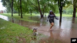 A woman walks her dog through a footpath flooded by Tropical Storm Henri in Bushnell Park in Hartford, Connecticut, on Aug. 22, 2021.
