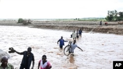 FILE - People wade through floodwaters in the aftermath of Tropical Cyclone Freddy in Phalombe, southern Malawi on March 18, 2023.