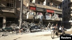 People ride a cart pulled by a horse near the damaged al-Hakeem hospital, in the rebel-held besieged area of Aleppo, Syria, Nov. 19, 2016. 