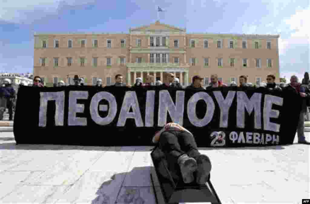 Protesters hold a banner reads ''We are dying- Feb. 23'' during a rally outside the Greek Parliament in Athens, Wednesday, Feb. 23, 2011. More than 30,000 protesters attended the Athens rally, which had been peaceful before the clashes broke out. Proteste
