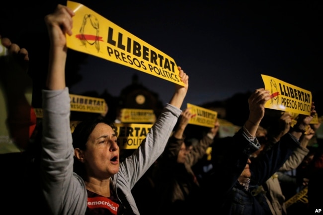 Afuera de la Corte Nacional en Madrid, personas levantan "esteladas" o banderas de la independencia de Cataluña en apoyo a los exmiembros del gobierno regional ordenados a permanecer detenidos por posibles cargos de rebelión, Nov. 2, 2017.