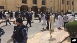 FILE - Security forces, officials and civilians gather outside of the Imam Sadiq Mosque after a deadly blast struck after Friday prayers in Kuwait City, Kuwait, June 26, 2015. 