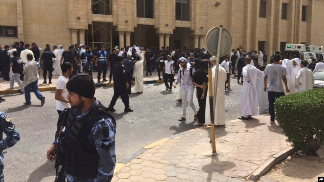 FILE - Security forces, officials and civilians gather outside of the Imam Sadiq Mosque after a deadly blast struck after Friday prayers in Kuwait City, Kuwait, June 26, 2015. 
