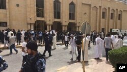 Pasukan keamanan dan jamaah berkumpul di luar masjid pasca pemboman masjid Imam Sadiq di Kuwait City, hari Jumat (26/6).