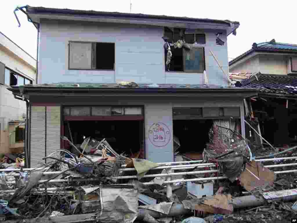 A red sign painted on a house shows it has been searched for survivors - this one by U.S. rescue teams in Kamaishi, Japan, March 17, 2011 (VOA - H. Ridgwell)