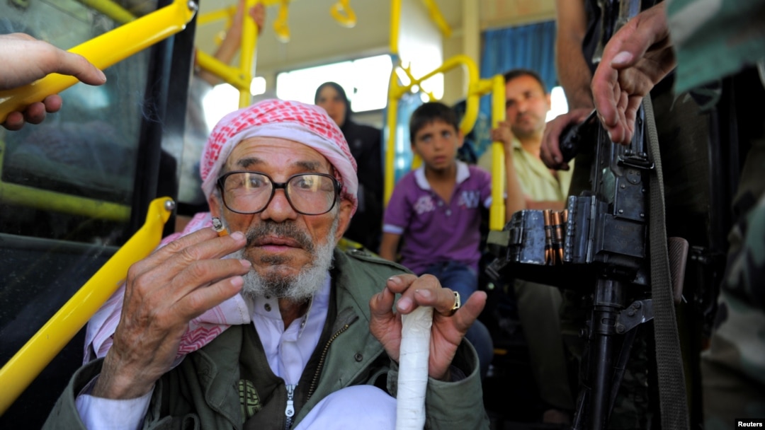 Passengers board a bus awaiting evacuation from the besieged Damascus suburb of Daraya, Aug. 26, 2016, following an agreement between rebels and Syria's government.