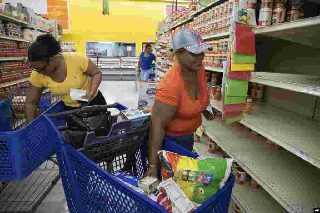 Mujeres compran suministros ante la llegada del huracán Dorian, en Freeport, Bahamas, el viernes 30 de agosto de 2019. (AP Foto/Tim Aylen)