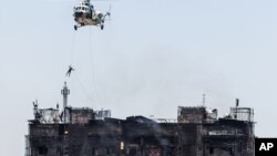 A rescue worker gets on a roof of an apartment building after a fire in Baku, Azerbaijan, Tuesday, May 19, 2015. 