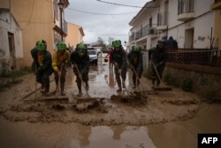 Members of the INFOCA (Andalusia Fire Prevention and Extinction Plan) clean a flooded street in Cartama, near Malaga, on Oct. 30, 2024, after heavy rains hit southern Spain.