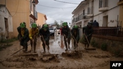 Members of the INFOCA (Andalusia Fire Prevention and Extinction Plan) clean a flooded street in Cartama, near Malaga, Oct. 30, 2024, after heavy rains hit southern Spain.