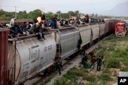 FILE - Central American migrants ride a freight train during their journey toward the U.S.-Mexico border in Ixtepec, Mexico, July 12, 2014. The migrants pay thousands of dollars per person for the illegal journey across thousands of miles in the care of smuggling networks that in turn pay off government officials, gangs operating on trains and drug cartels controlling the routes north.