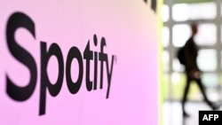 FILE - A person walks past a banner with an Spotify logo at the Frankfurt, Germany, book fair Oct. 17, 2024.