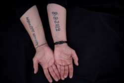 FILE - Leila Shamo displays tattoos she made while enslaved by Islamic State militants at her home near Khanke Camp, near Dohuk, Iraq, Aug. 29, 2019. Her left arm shows the names of her husband and two sons; her right arm - the date of her capture.
