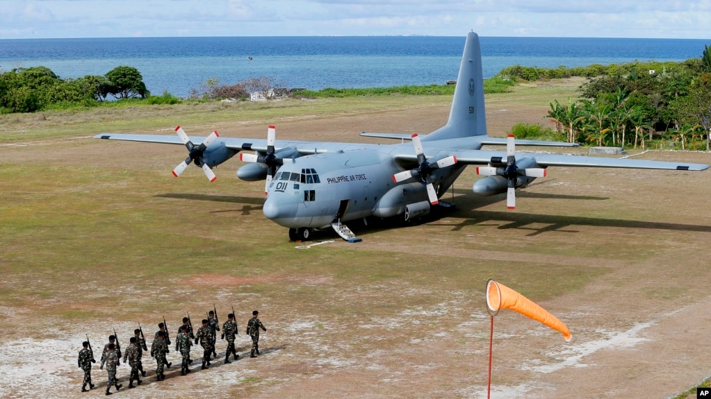 FILE - Philippine troops march as a Philippine Air Force C-130 transport plane carrying Philippine Defense Secretary Delfin Lorenzana, Armed Forces Chief Gen. Eduardo Ano and other officials, sits on the tarmac at the Philippine-claimed Thitu Island off the disputed Spratlys chain of islands in the South China Sea, April 21, 2017 in western Philippines. 