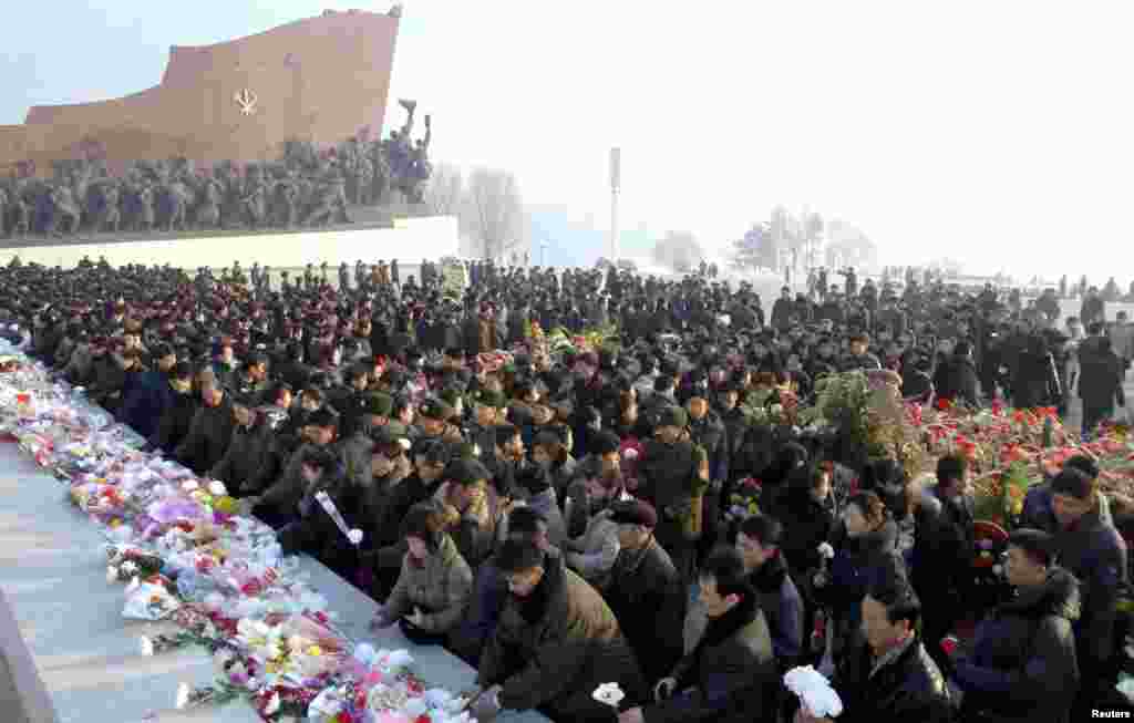 Warga Korea Utara menyimpan bunga di depan patung-patung Kim Il Sung dan Kim Jong Il di bukit Mansudae di Pyongyang, pada acara peringatan dua tahun kematian Kim Jong Il (17/12). (KCNA)