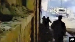 Protesters watch as tear gas fills a street during a demonstration in Deraa in this image from amateur video taken on Mar 23 2011 and posted on a social media website