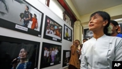 Burma's pro-democracy leader Aung San Suu Kyi looks at pictures of herself at a photo exhibition held at the National League for Democracy's office in Rangoon, Burma, May 23, 2011