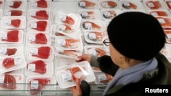 FILE - A customer picks fish fillet as she visits the fish department of a hypermarket of French grocery retailer Auchan in Moscow, January 15, 2015.