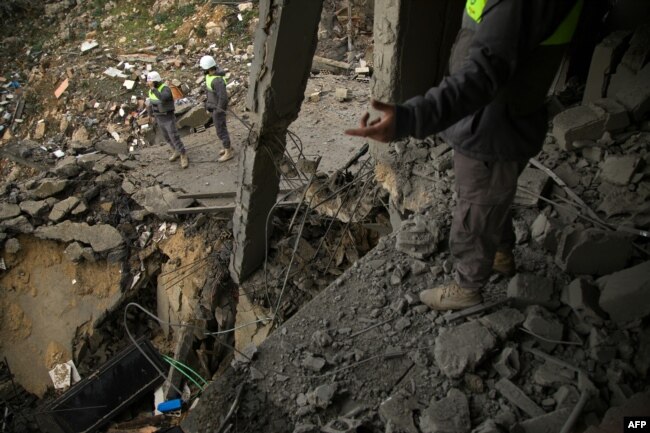 FILE - Civil defence workers assess the destruction caused by an overnight Israeli bombing in Al- Khiam in southern Lebanon on January 31, 2024.