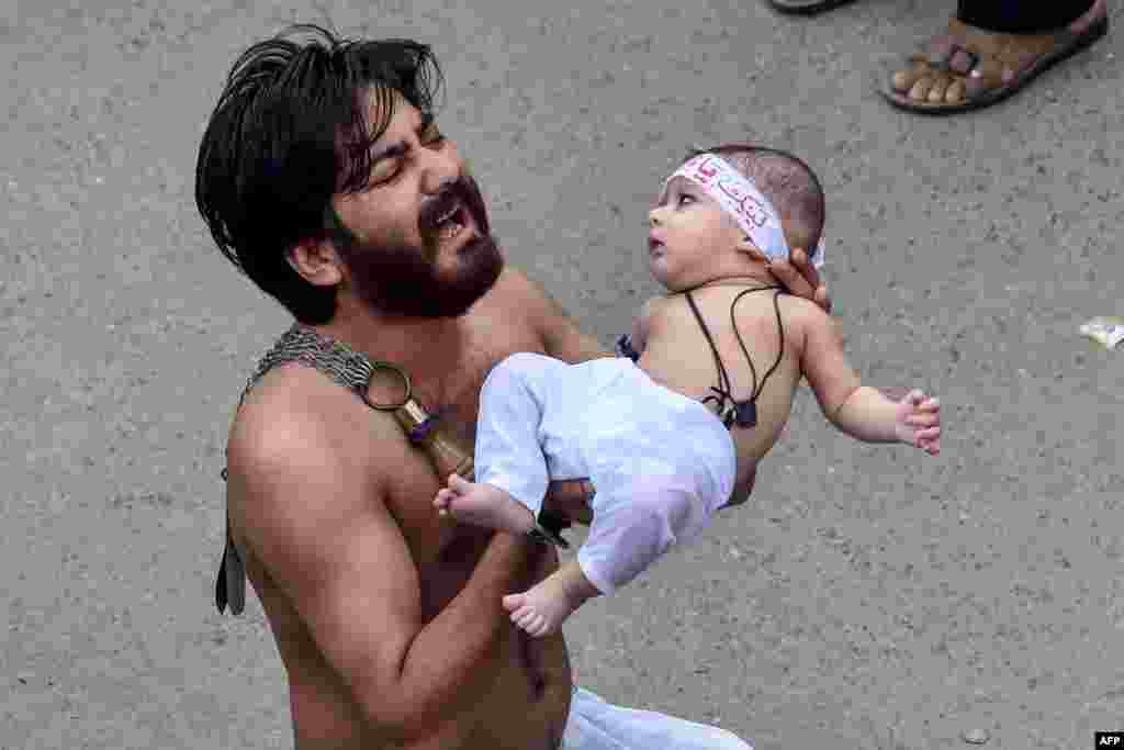 A Shi&#39;ite Muslim holds his son before starting flagellating himself for an Ashura procession during the month of Muharram in Lahore, Pakistan.