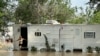 Una mujer sale de una casa móvil en un área no incorporada en el este del condado de Harris, cerca de Houston, el sábado 4 de mayo de 2024 por la tarde. Intensas lluvias han provocado fuertes inundaciones en la región.