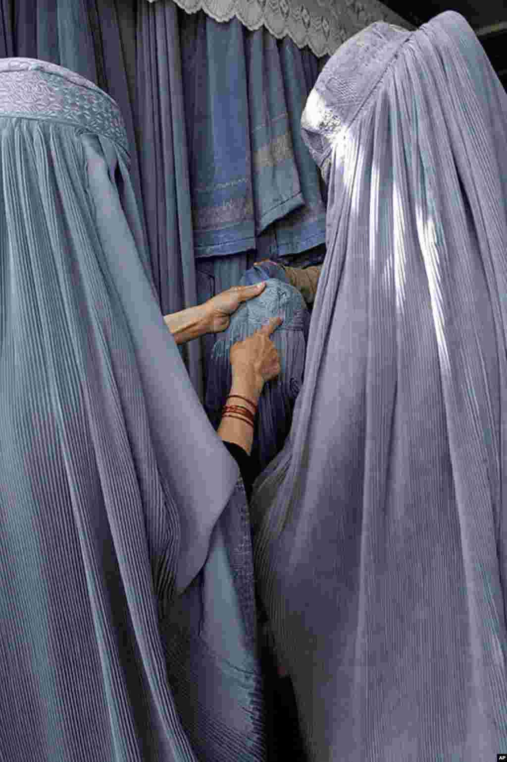 Two women examine the cap of a burqa in a shop in Kabul on April 17, 2007. Despite advances in women's rights since the U.S.-led invasion of late 2001 led to the toppling of the Taliban regime, most Afghan women, especially outside the capital, still opt 
