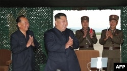 This picture taken on August 24, 2019 and released on August 25 by North Korea's official Korean Central News Agency (KCNA) shows North Korean leader Kim Jong Un (C) celebrating the test-firing of a 'newly developed super-large multiple rocket launcher' at an undisclosed location