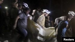 Các thành viên dân phòng khiêng một nạn nhân ra khỏi hiện trường sau vụ không kích bệnh viện tại thị trấn al-Sukari Aleppo, Syria, ngày 27/4/2015.