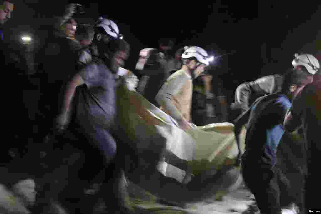 Civil defense members carry a casualty after an airstrike at a field hospital in the rebel held area of al-Sukari district of Aleppo, April 27, 2016.