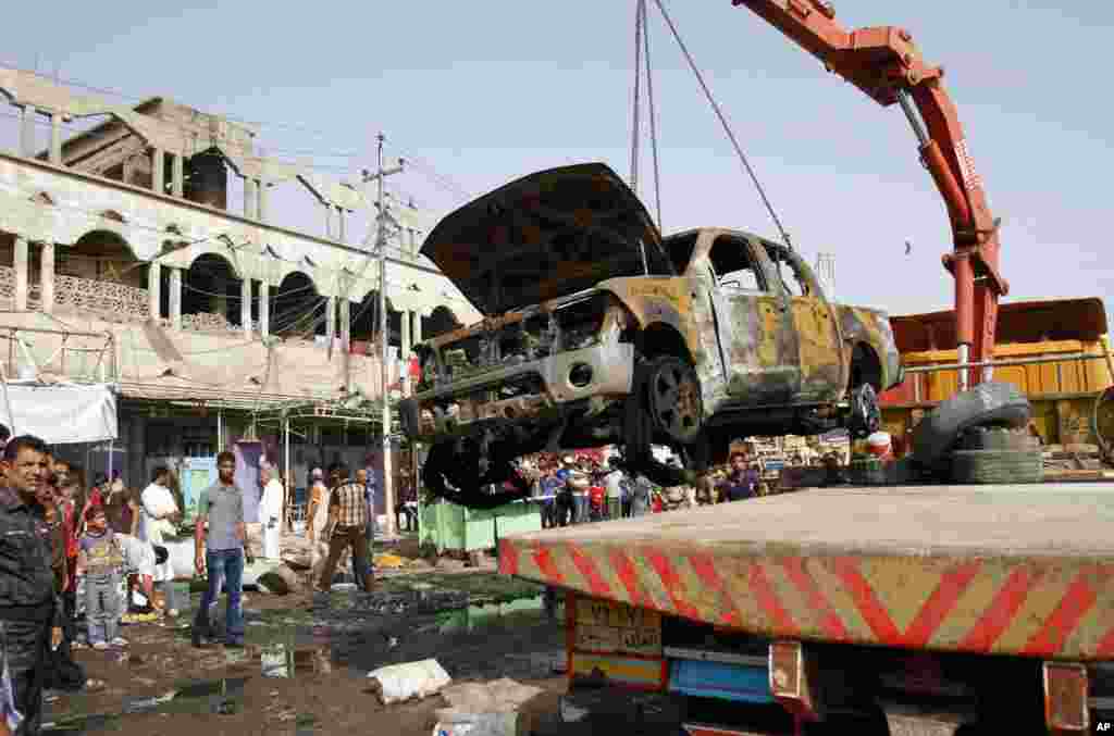 A wrecked truck is removed from the site of a car bomb attack in front of a crowded popular restaurant in Basra, Iraq, May 20, 2013.