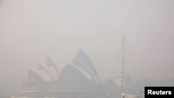 FILE - A sailing boat passes the Sydney Opera House as smoke from bushfires blankets the city. 