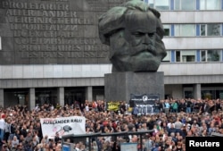 FILE - Right-wing supporters protest after a German man was stabbed last weekend in Chemnitz, Germany, Aug. 27, 2018. The banner reads, "Criminal foreigners out."