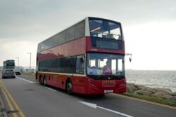 Sebuah bus tingkat melintas di jalan tepi laut dekat bandara di Hong Kong, Sabtu, 16 Oktober 2021. Bagi warga yang merindukan kegiatan bepergian yang santai, sebuah agen perjalanan kini menawarkan solusinya, yakni Bus Tidur. (Foto: AP)