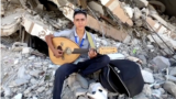 In this frame captured from video, Palestinian teenager Youssef Saad sits on the rubble of his house as he plays oud to bring joy to children, amid Israel-Hamas conflict, in Jabalia refugee camp in the northern Gaza Strip September 2, 2024. (REUTERS/Mahmoud Issa)