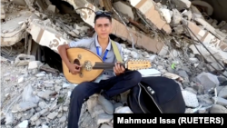 In this frame captured from video, Palestinian teenager Youssef Saad sits on the rubble of his house as he plays oud to bring joy to children, amid Israel-Hamas conflict, in Jabalia refugee camp in the northern Gaza Strip September 2, 2024. (REUTERS/Mahmoud Issa)