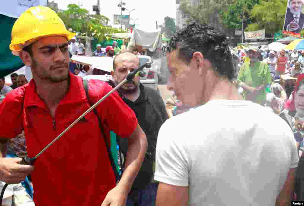 A supporter of Morsi is doused with water on a hot day in Cairo, July 12, 2013. 