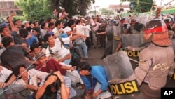 Indonesian students fall as riot policemen charge-in during an anti-government demonstration that turned violent at the gate of the Sahid University in Jakarta 29 April, 1998. Clashes erupted as some 300 students who were demanding President Suharto to s
