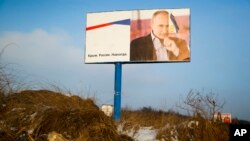 FILE - A partially damaged billboard with a portrait of Russian President Vladimir Putin is seen on a roadside near Simferopol, Crimea, Jan. 24, 2016. The billboard reads: "Crimea. Russia. Forever."