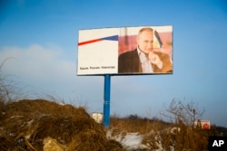 FILE - A partially damaged billboard with a portrait of Russian President Vladimir Putin is seen on a roadside near Simferopol, Crimea, Jan. 24, 2016. The billboard reads: "Crimea. Russia. Forever." The slogan was reinforced this week by Russian Foreign Ministry spokeswoman Maria Zakharova, who said “Crimea is territory belonging to the Russian Federation. That is it."