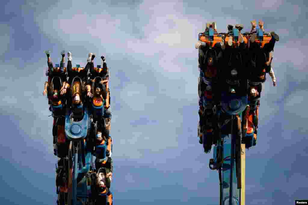 People wearing face masks enjoy a fun ride in the Happy Valley amusement park in Beijing, China.