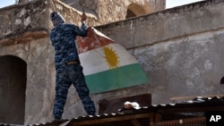 An Iraqi soldier removes a Kurdish flag from Altun Kupri on the outskirts of Irbil, Iraq, Oct. 20, 2017.