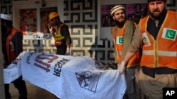 Pakistani rescue workers remove a body from the site of a grenade attack at a movie theater in Peshawar, Feb. 11, 2014.
