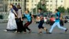 Jeunes égyptiens harcelant des femmes qui traversent la route au Caire, en Égypte, le 20 août 2012. L'un d'eux va jusqu'à la toucher sur les fesses, ce qui arrive fréquement en Egypte, sans que les autorités ne réagissent ou n'interviennent (Photo AP/Ahmed Abd el Latif)