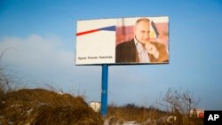 Papan reklame bergambarkan Presiden Rusia Vladimir Putin di pinggir jalan dekat Simferopol, Krimea, 24 Januari 2016. Papan itu bertuliskan: "Krimea. Rusia. Selamanya." (AP/Sergei Grits)