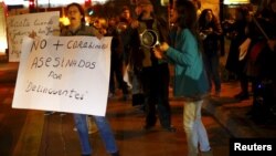 A woman holds up a placard that reads "No more policemen murdered by delinquents" as they beat cooking utensils during a rally against what participants say is an explosion in crime, Santiago, July 29, 2015.