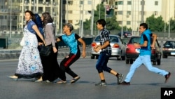 Jeunes égyptiens harcelant des femmes qui traversent la route au Caire, en Égypte, le 20 août 2012. L'un d'eux va jusqu'à la toucher sur les fesses, ce qui arrive fréquement en Egypte, sans que les autorités ne réagissent ou n'interviennent (Photo AP/Ahmed Abd el Latif)