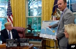 President Donald Trump (L) listens as FEMA Administrator Brock Long, center, talks about Hurricane Florence in the Oval Office of the White House in Washington, Sept. 11, 2018, as Homeland Security Secretary Kirstjen Nielsen listens at right.