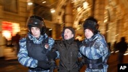 Polisi menahan seorang demonstran ketika berunjukrasa di Moskow, Rusia, 30 Desember 2014.